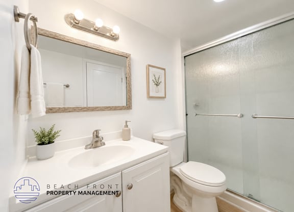 A bathroom with a white toilet, sink, and mirror.