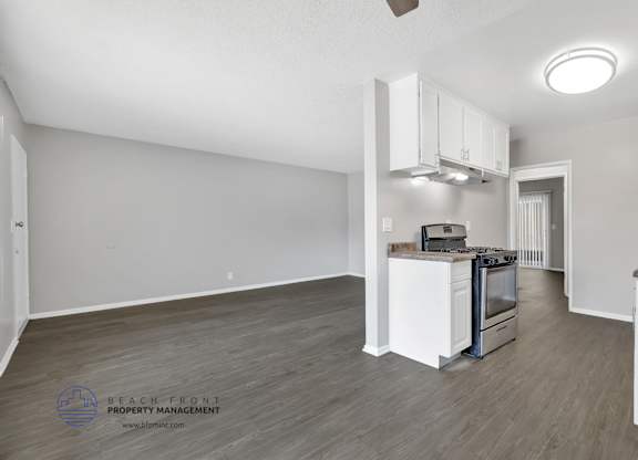 A spacious kitchen with white cabinets and a stainless steel stove.