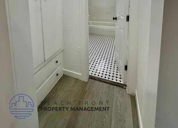 A white bathroom with a mirror and a wooden floor.