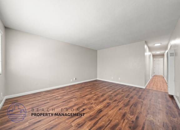 A room with wooden flooring and a logo for Beach Front Property Management.