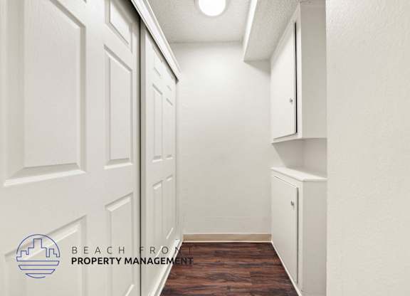 A hallway with white doors and a logo for Beachfront Property Management.