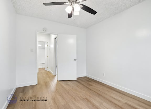 A room with a ceiling fan and wooden flooring.