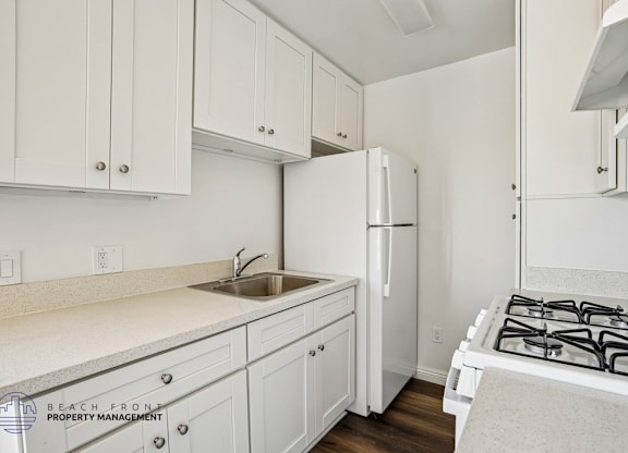 A kitchen with white cabinets and a white stove top.