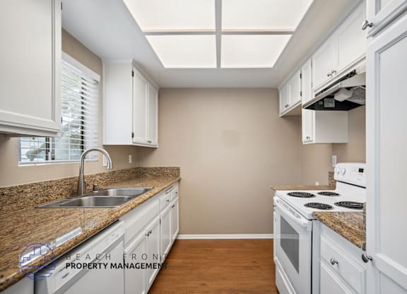 A kitchen with white cabinets and a granite countertop.