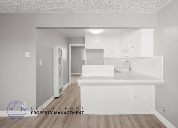 A white kitchen with a logo for Beach Front Property Management.