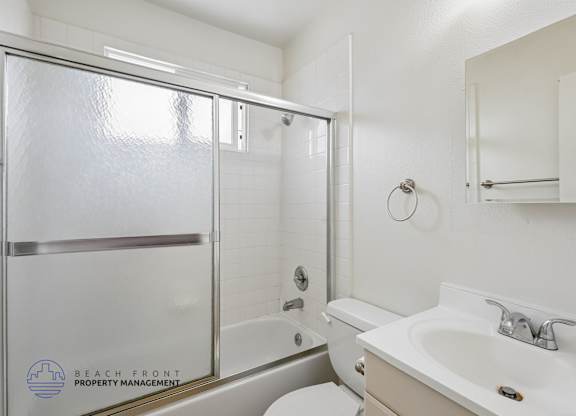 A bathroom with a sink, toilet, and a shower with a glass door.