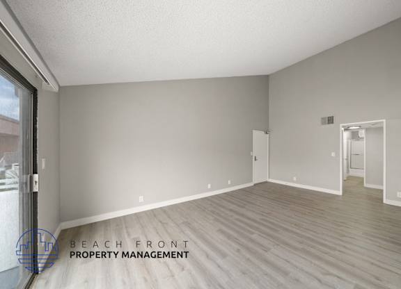 the spacious living room with wood flooring and a large window