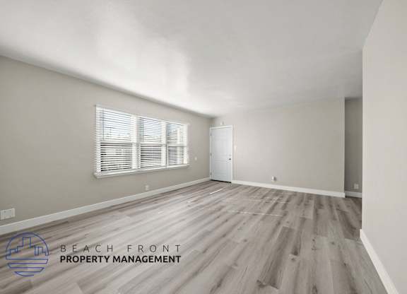A room with wooden flooring and a window with blinds.