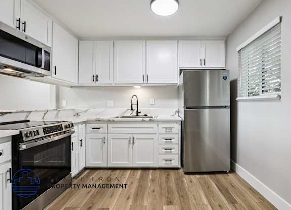 A modern kitchen with white cabinets and stainless steel appliances.