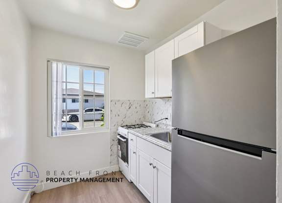 A kitchen with a stainless steel refrigerator and white cabinets.