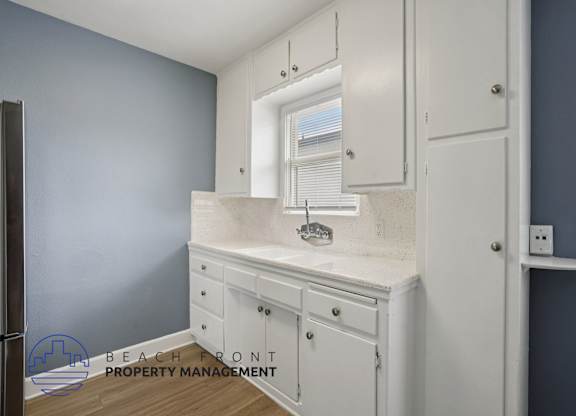 A bathroom with a sink, mirror, and cabinets.