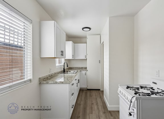 A kitchen with white cabinets and a white stove top oven.