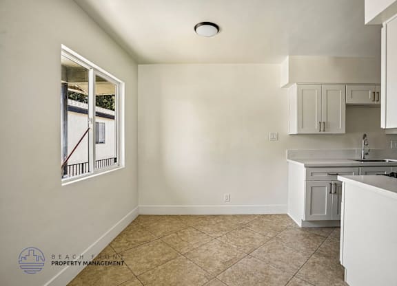 A kitchen with white cabinets and a window overlooking a balcony.