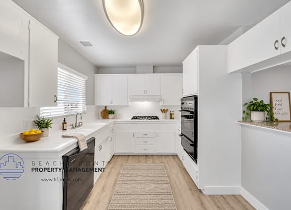 A clean, white kitchen with a skylight and a fridge on the left.