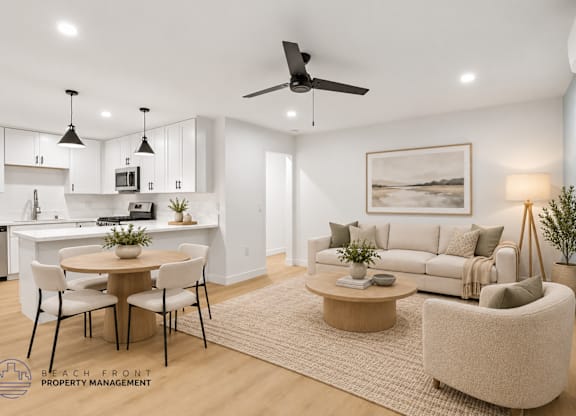 A well-lit, modern living room with a dining area and kitchen in the background.