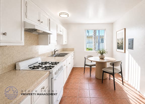 A kitchen with a stove top oven and a dining table with chairs.