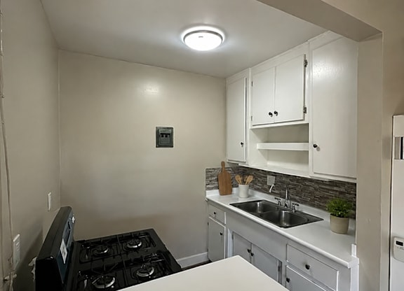 A small kitchen with a black stove top and white cabinets.