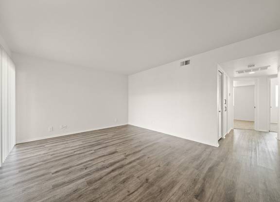 A room with wooden flooring and white walls.
