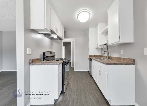 A kitchen with white cabinets and a wooden floor.