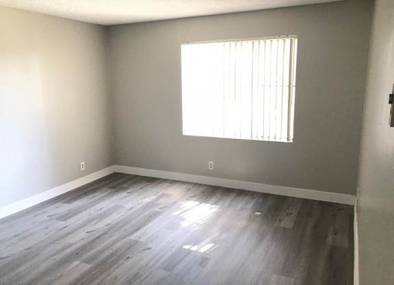 A room with a window and wooden flooring.