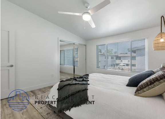 a bedroom with a large white bed and a ceiling fan