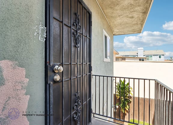 A black door with a metal handle and a window is on a balcony.