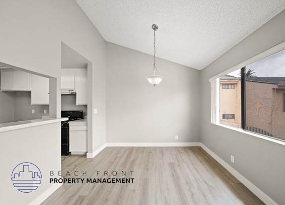 an empty living room and kitchen with wood flooring and a window