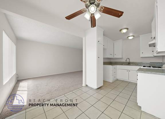 A kitchen with white cabinets and a ceiling fan.