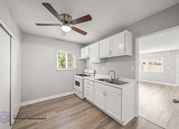 A kitchen with white cabinets and a ceiling fan.