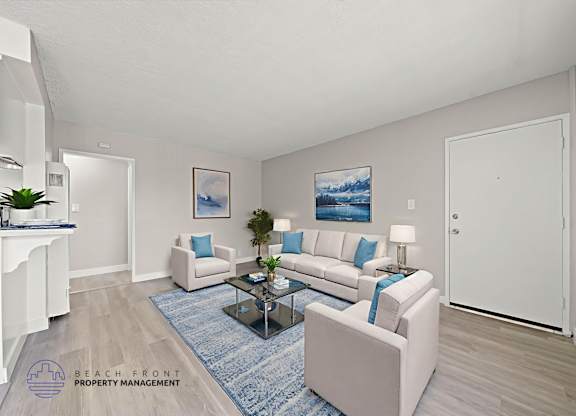 A living room with a white couch, a blue rug, and a painting on the wall.