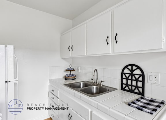 A kitchen with white cabinets and a checkered towel on the counter.