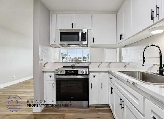 A kitchen with white cabinets and a black faucet.