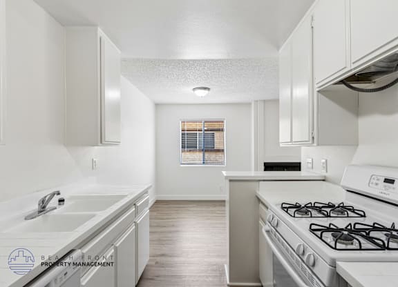 A kitchen with a stove, sink, and cabinets.