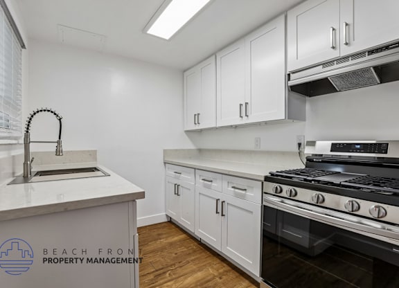A kitchen with white cabinets and a stove top oven.