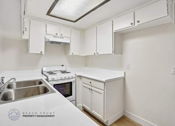 A kitchen with white cabinets and a stove top oven.