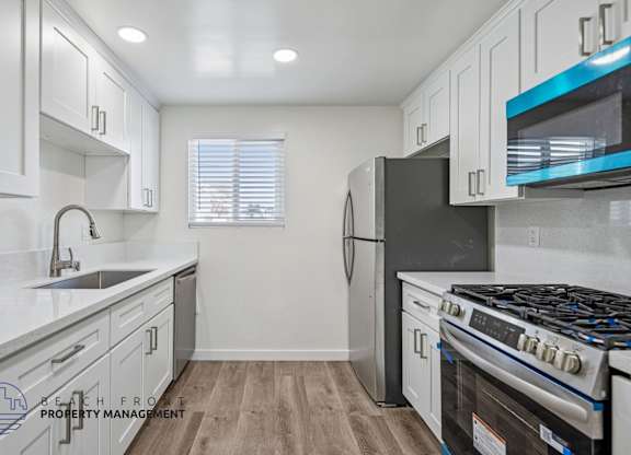 A kitchen with white cabinets and a black refrigerator.