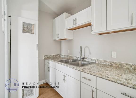 A kitchen with white cabinets and a granite countertop.