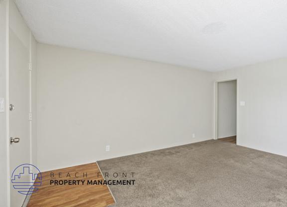 A room with a carpeted floor and a door on the right side.