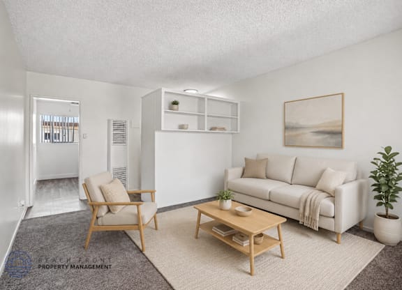 A living room with a white couch, a wooden coffee table, and a plant.