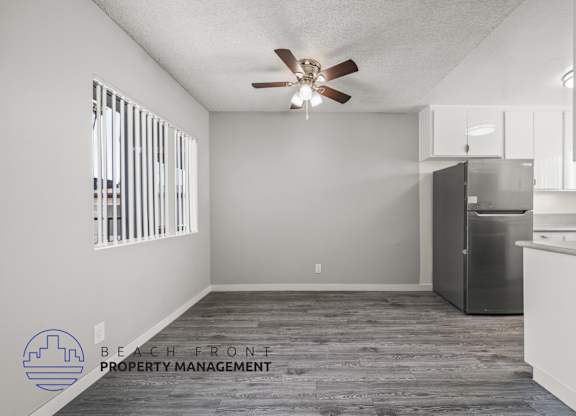 A spacious kitchen and living room with a ceiling fan and wooden flooring.