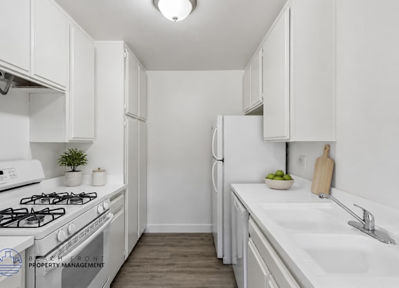 A white kitchen with a stove, sink, and refrigerator.