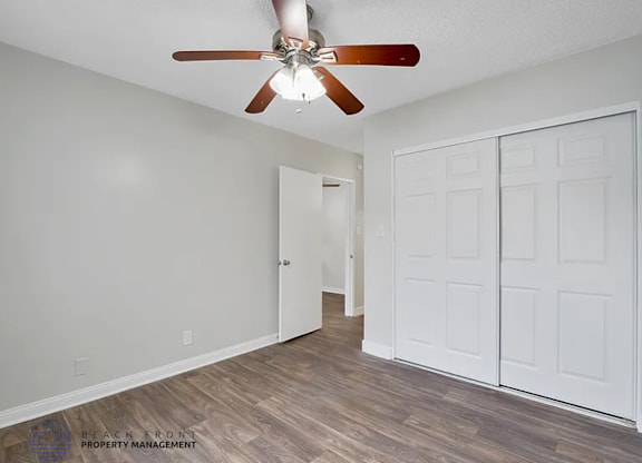 A room with a ceiling fan and a white door.