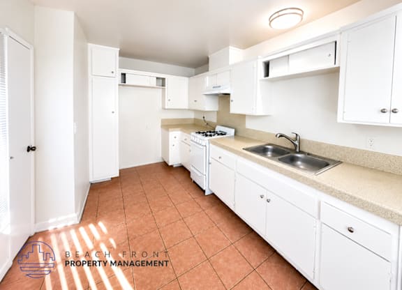 A kitchen with white cabinets and a tiled floor.