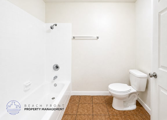 A white toilet sits next to a white bathtub in a small bathroom.