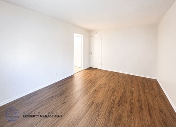 A room with wooden flooring and two doors.