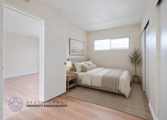 A bedroom with a bed, nightstand, and a plant.