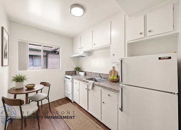 A kitchen with white cabinets and a refrigerator.