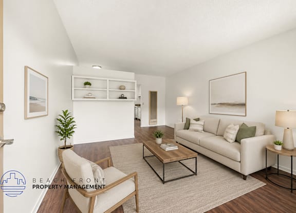 A living room with a white couch, a chair, a coffee table, and a plant.