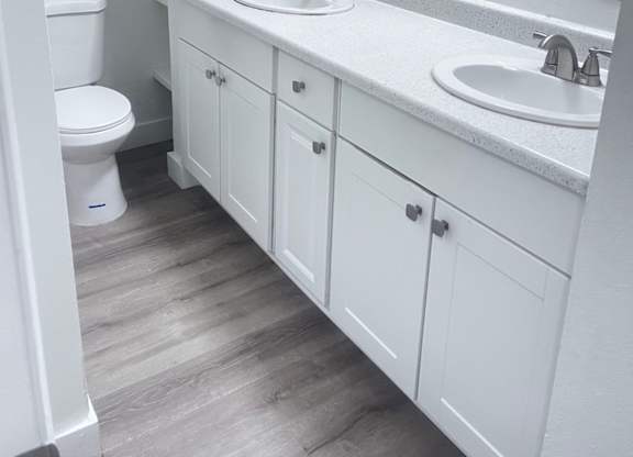 A white bathroom with a toilet, sink, and mirror.