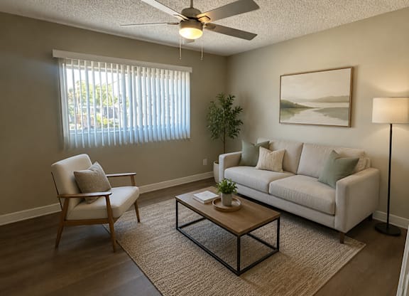 A living room with a white couch, a chair, a coffee table, and a ceiling fan.